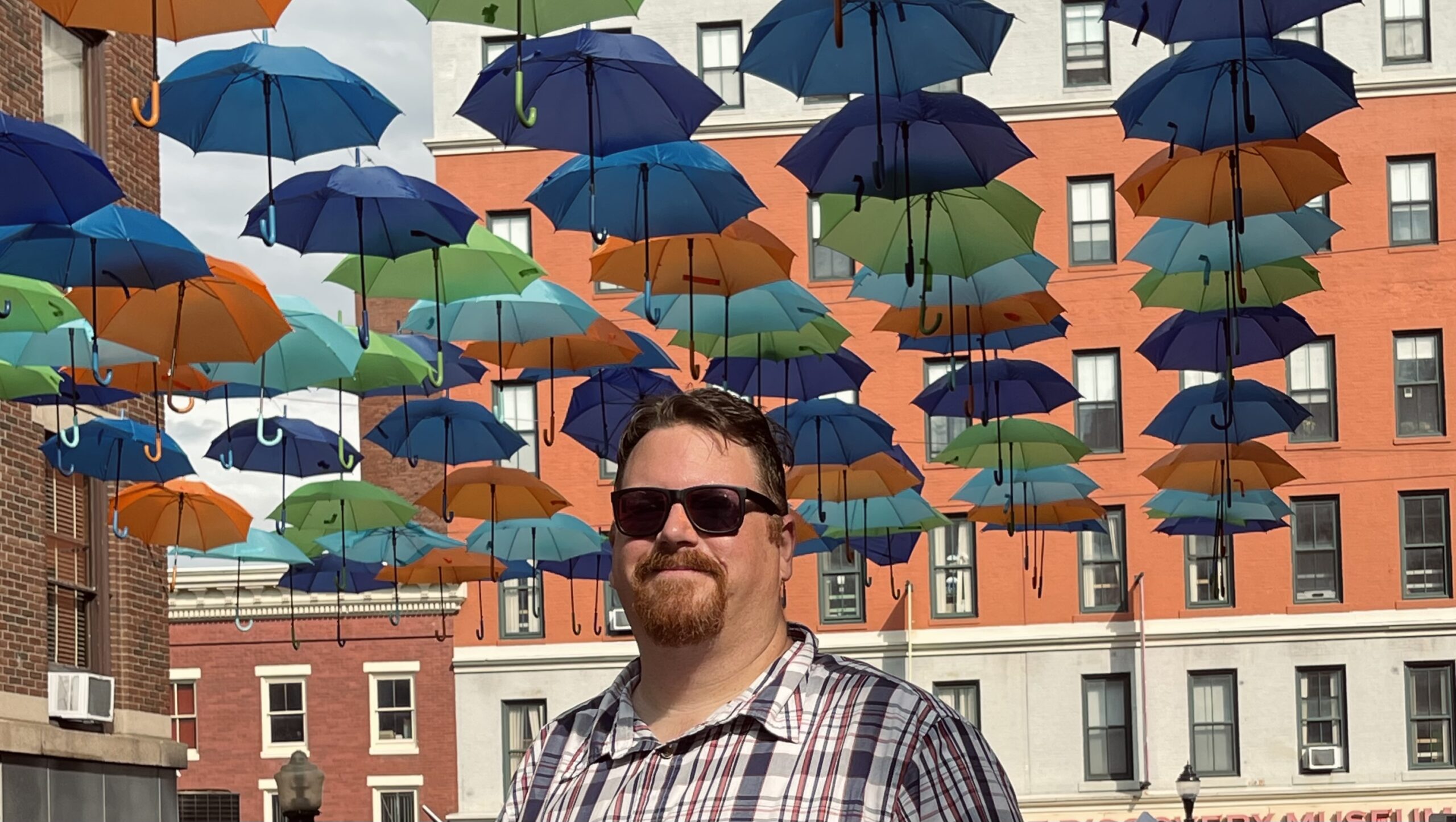 Michael Beck standing in front of the Umbrella Sky display over Cross Street in Downtown Bangor. 